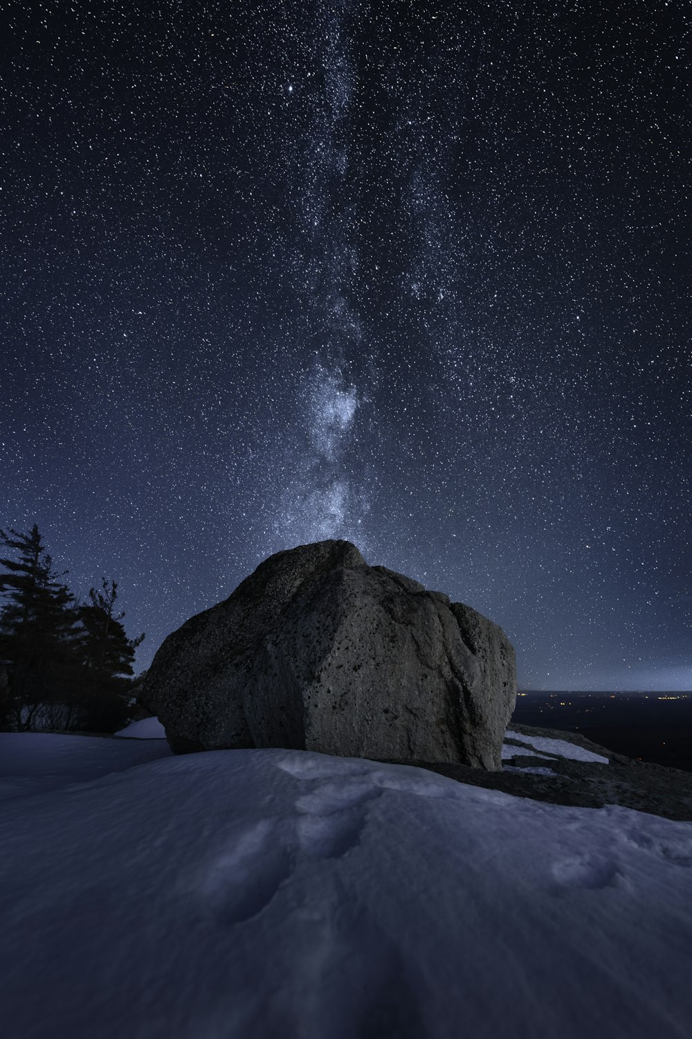 a rock in the snow under a night sky filled with stars