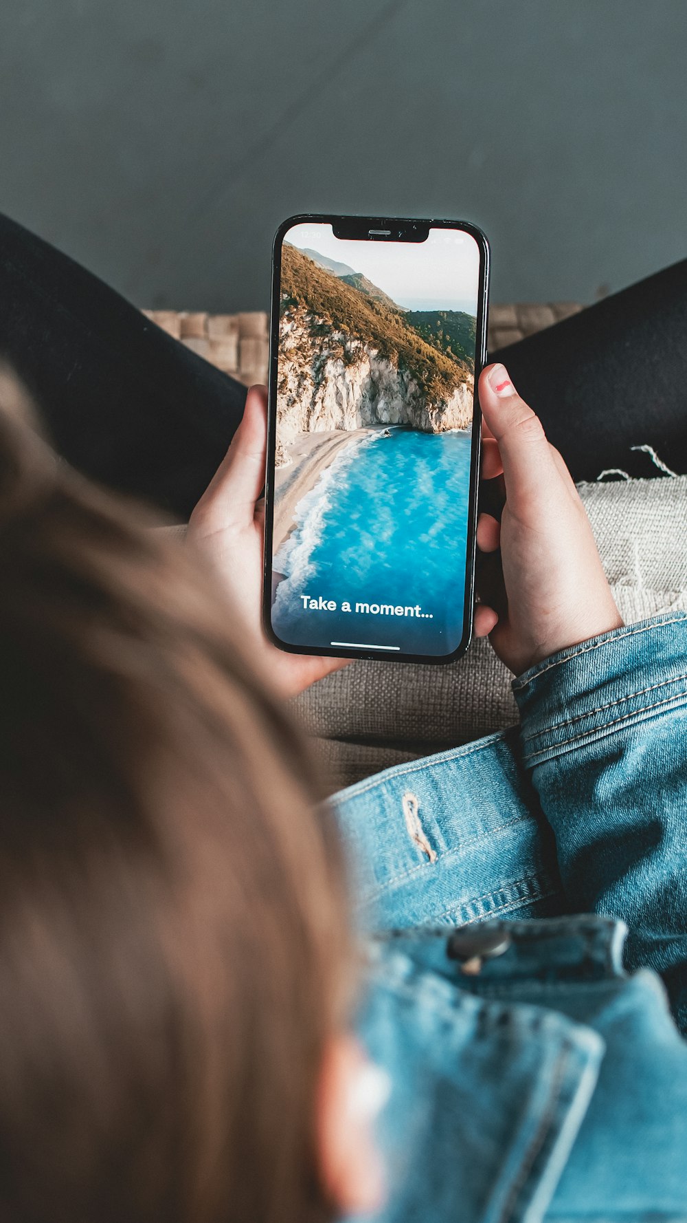 a person sitting on a couch holding a cell phone