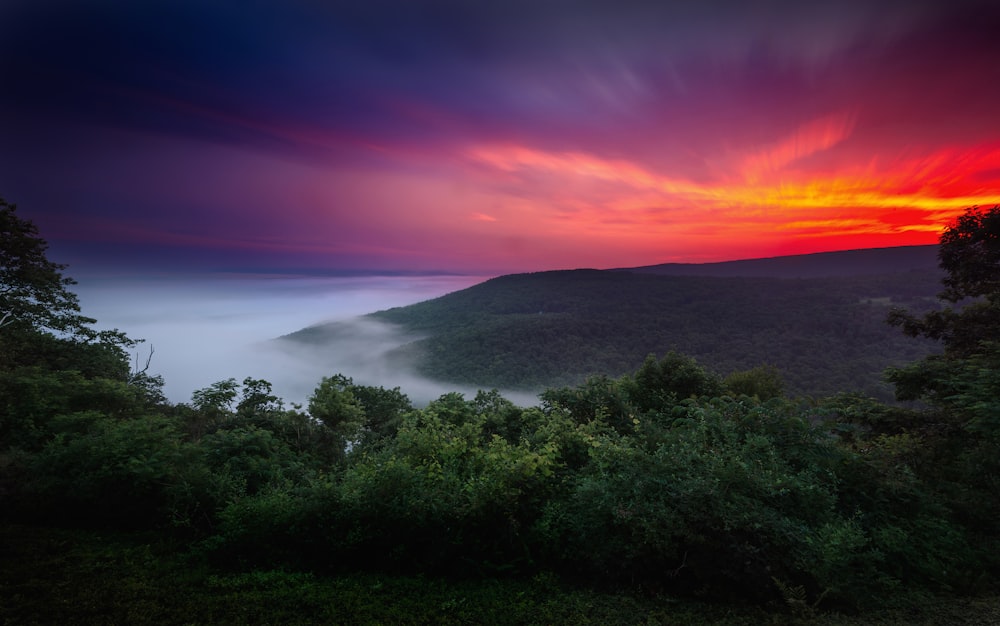 a colorful sunset in the mountains with clouds