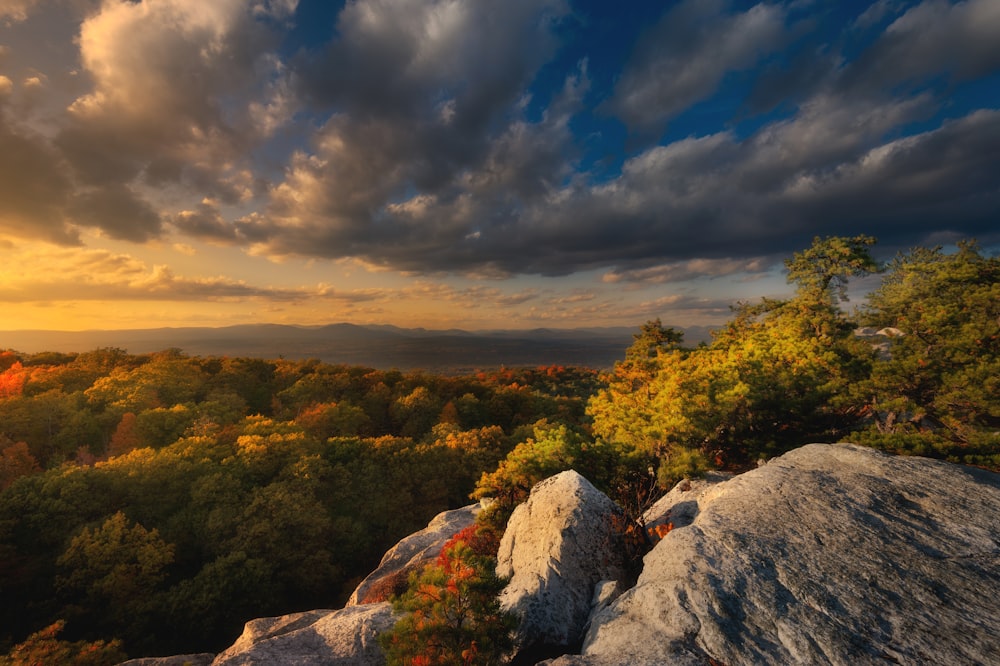 the sun is setting over the mountains and trees