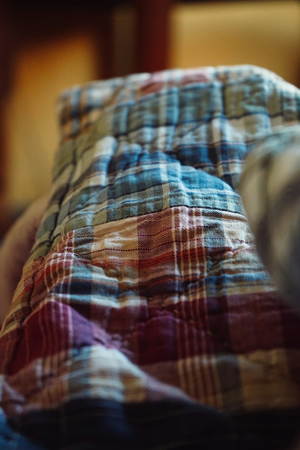 a person laying on a bed with a plaid comforter