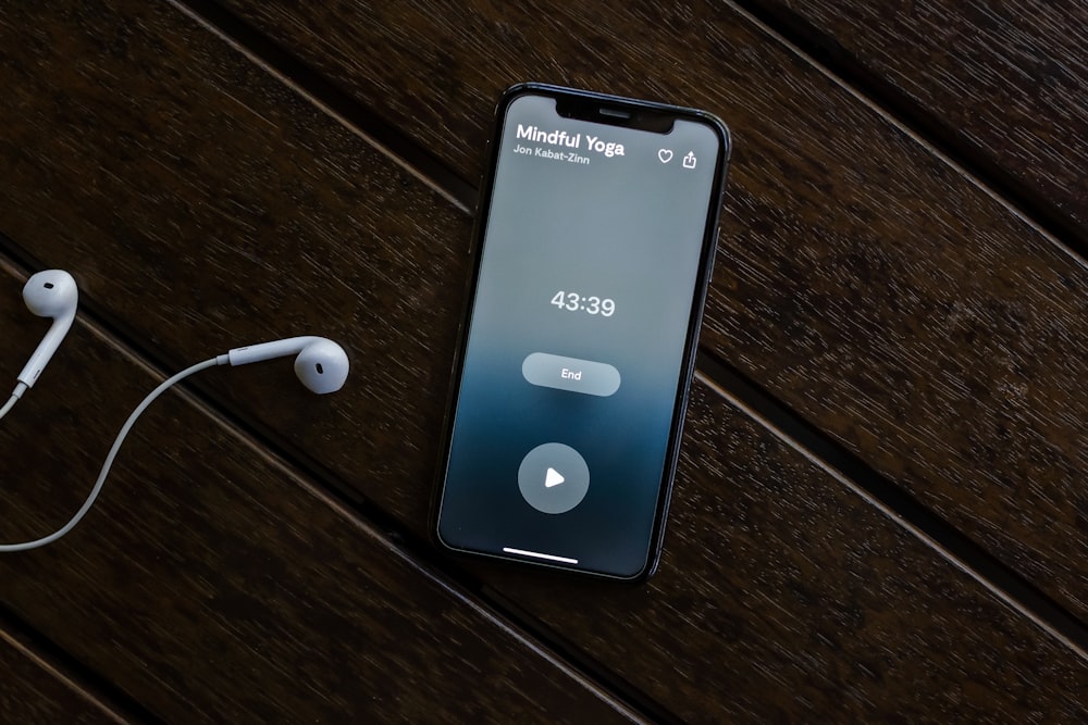 an iphone and ear buds on a wooden table