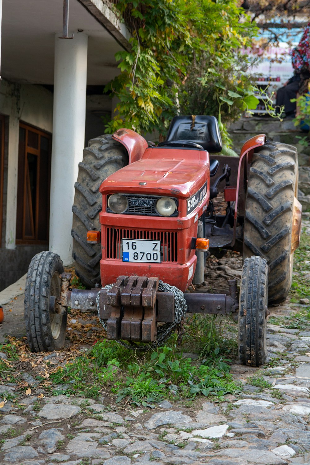 um trator vermelho estacionado ao lado de um edifício