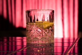 A close-up of a crystal whiskey glass catching golden light against a dark, elegant background.