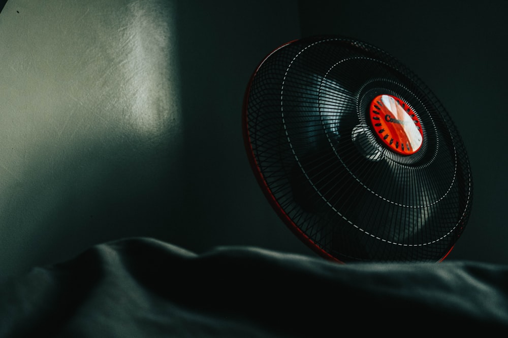 a fan sitting on top of a bed next to a window