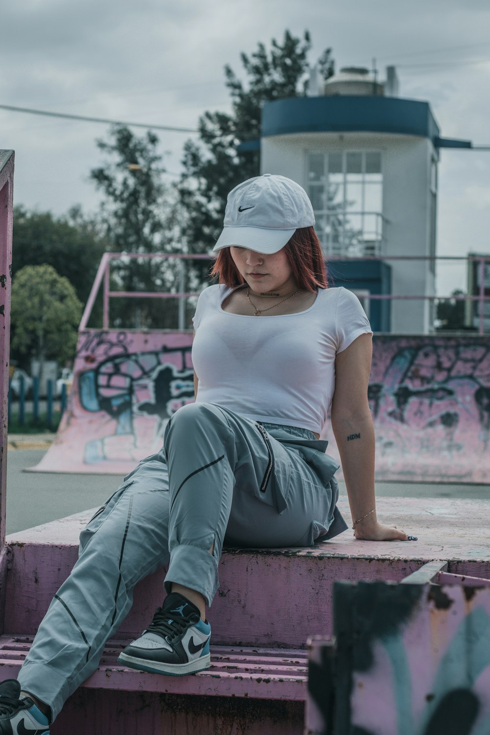 a woman with red hair sitting on a skateboard ramp