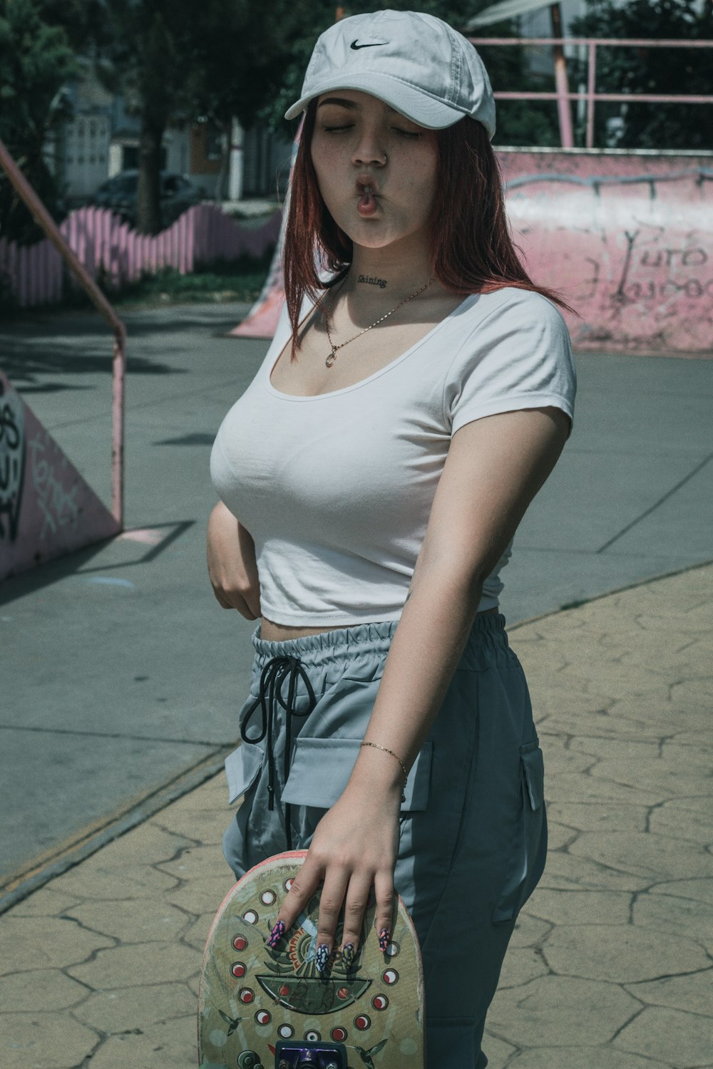 a woman holding a skateboard on a sidewalk