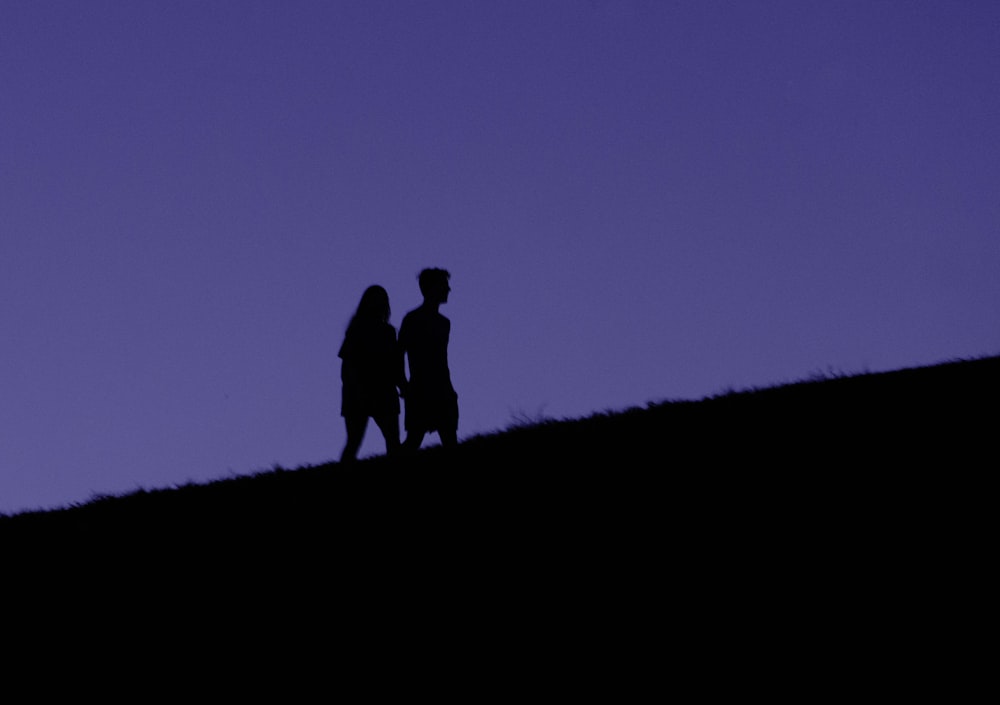 Un couple de personnes debout au sommet d’une colline