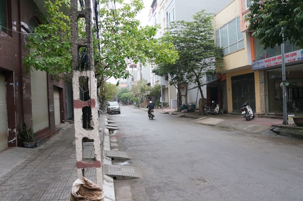 A rider enjoying a battcycles concept bike on a quiet city street with warm, off-white buildings in the background.