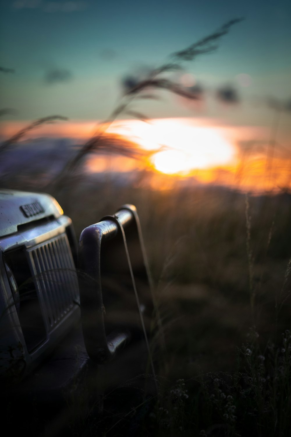 a truck parked in a field with the sun setting in the background