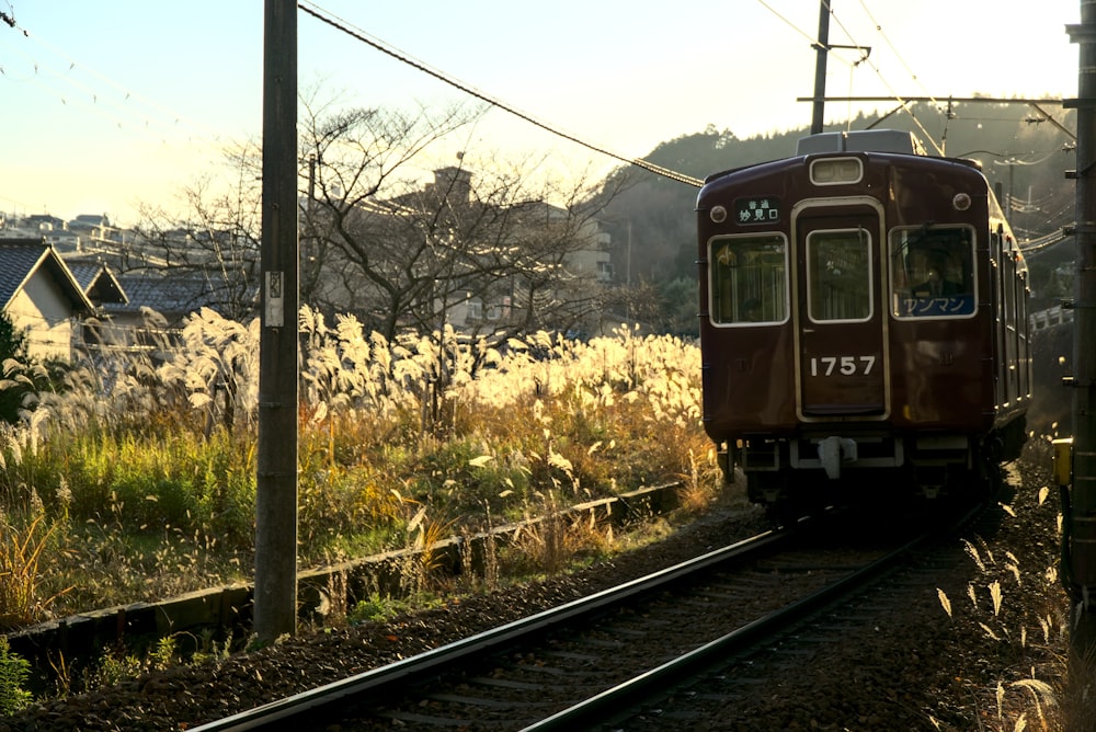 a red train traveling down train tracks next to a lush green field