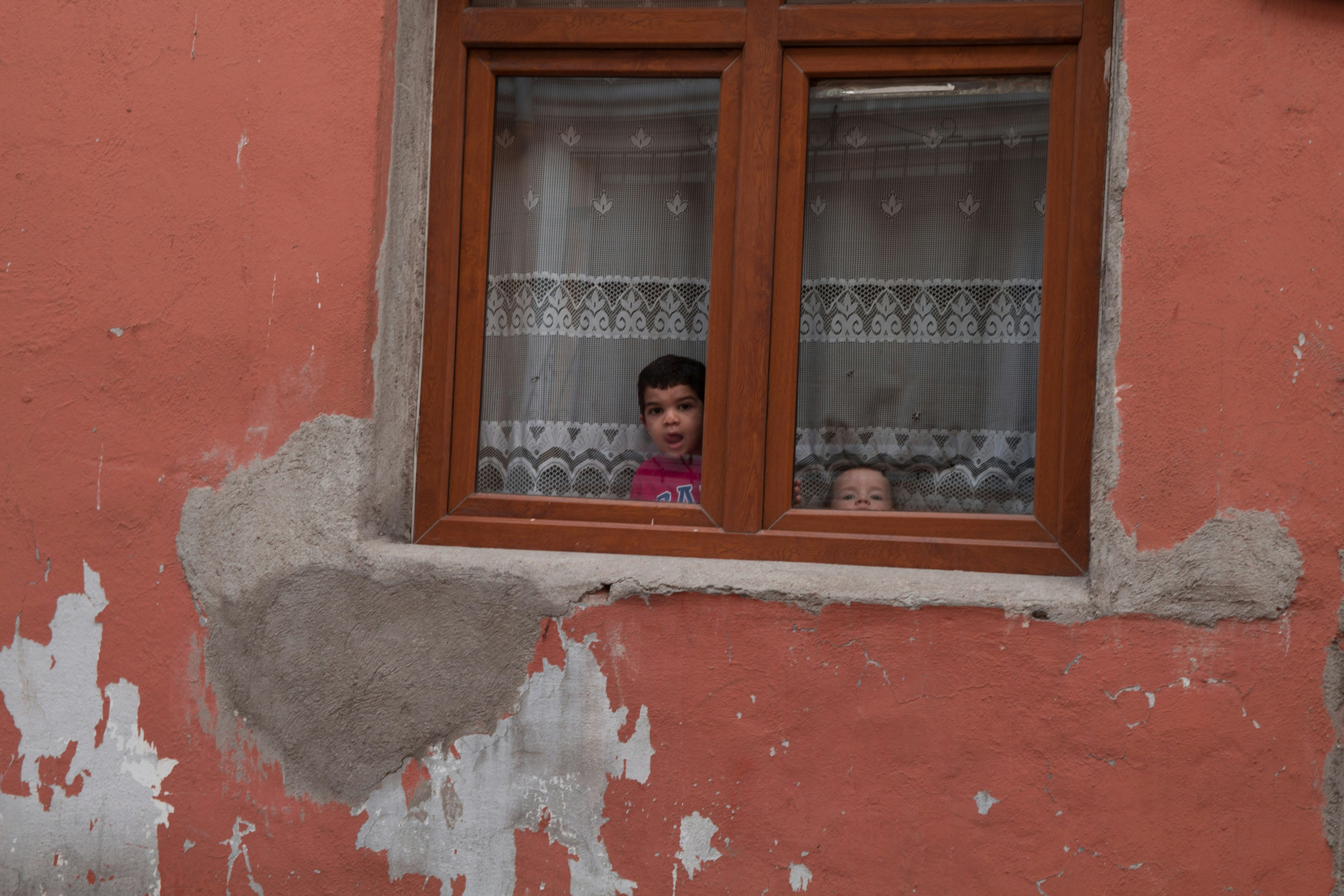 古い建物の窓から外を眺める2人の子供