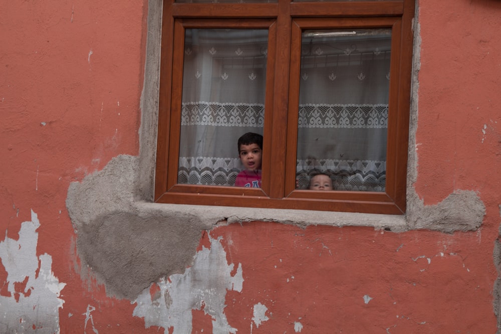 two children looking out of a window in an old building