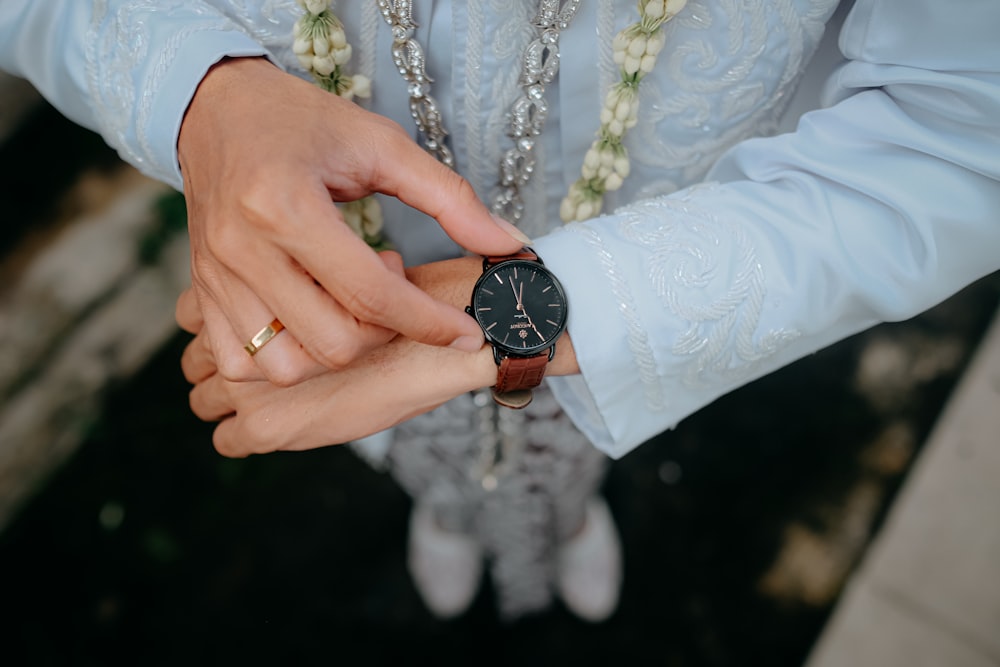 a man and woman holding hands with a watch on their wrist