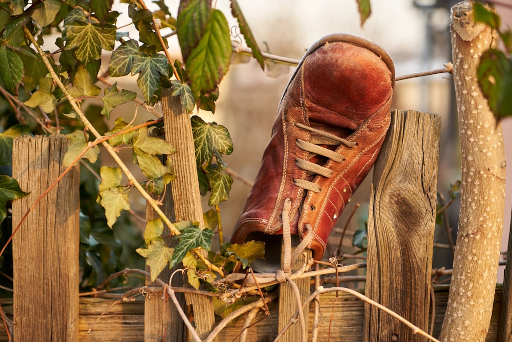 an old pair of shoes sitting on top of a wooden fence