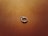 A solitaire diamond engagement ring rests on a textured, warm, brown surface. The surface has a subtle shine, complementing the brilliance of the diamond and the metallic band of the ring.