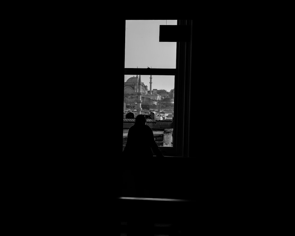 a black and white photo of a person looking out a window