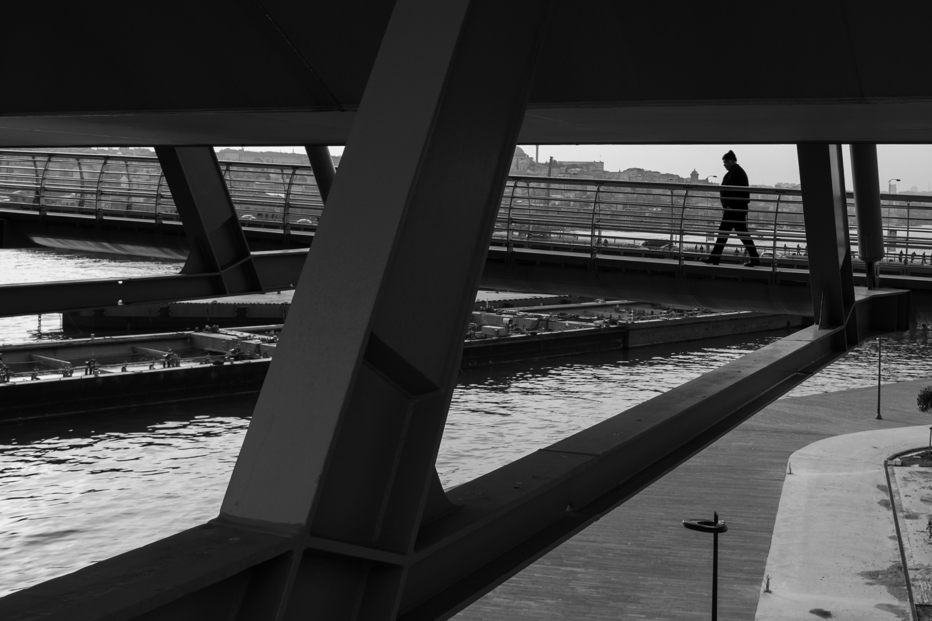 a man walking across a bridge over a river