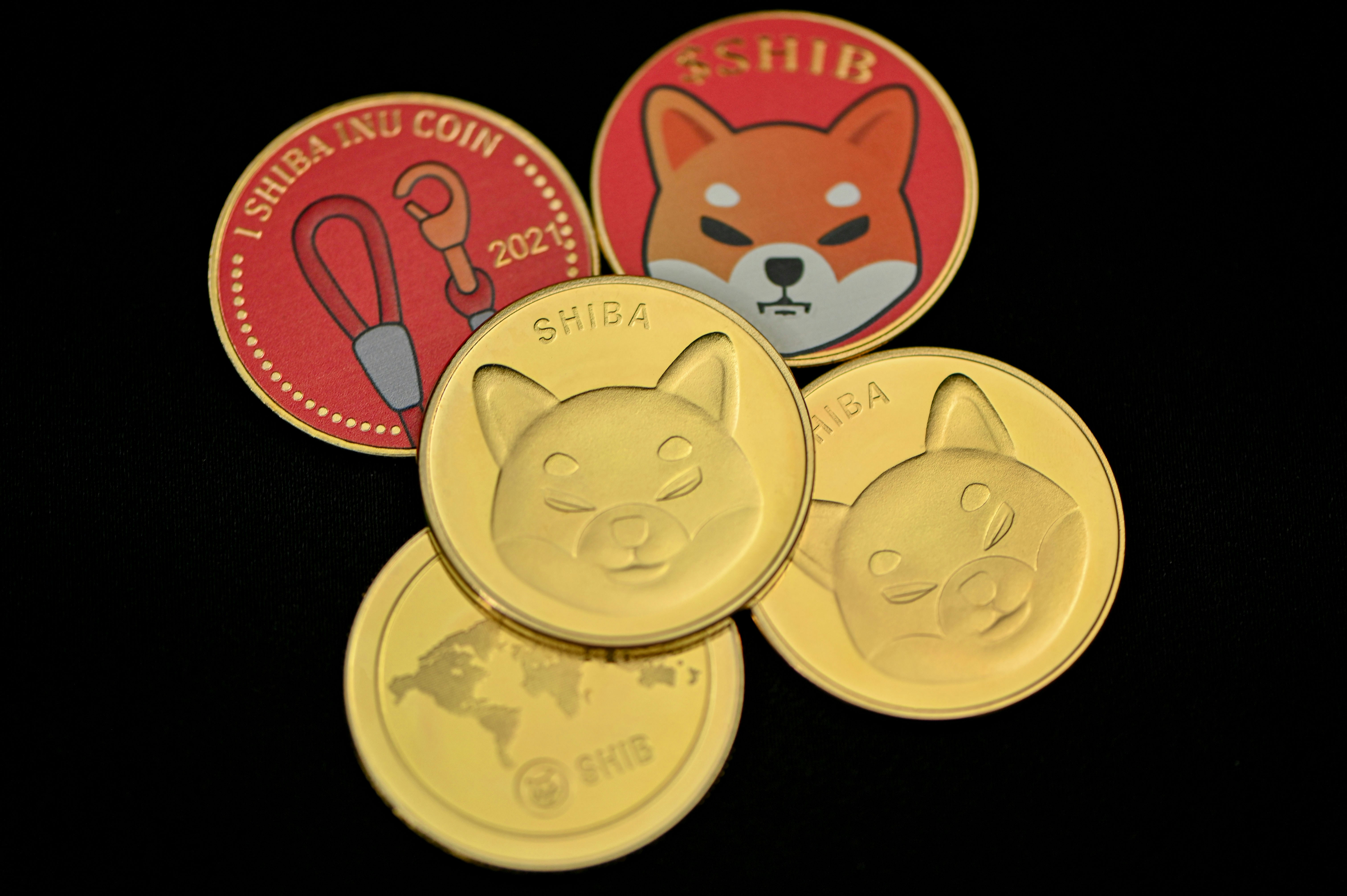 A group of SHIB coins are together on a black background