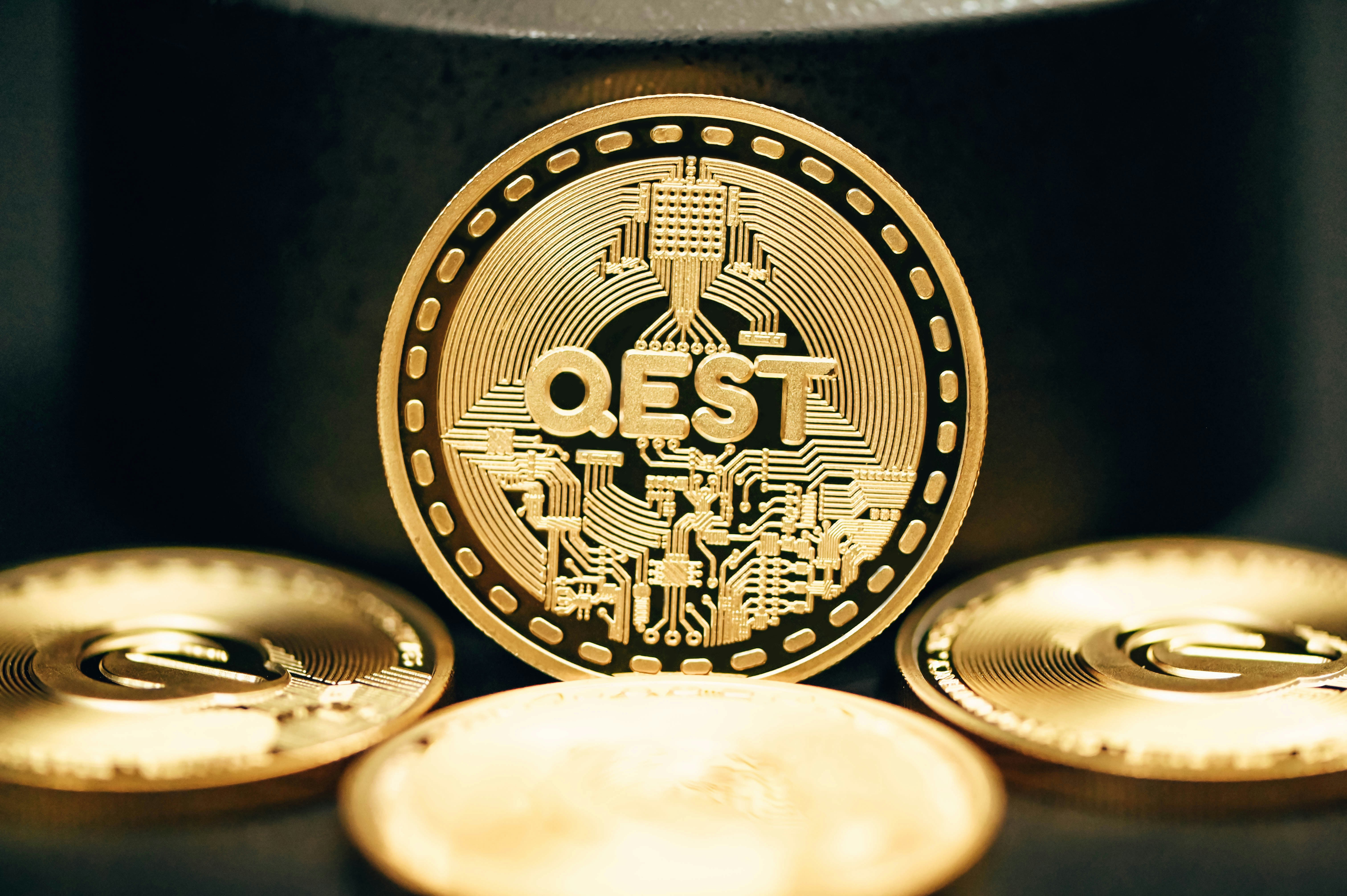 A pile of QEST coins are shining in the dark