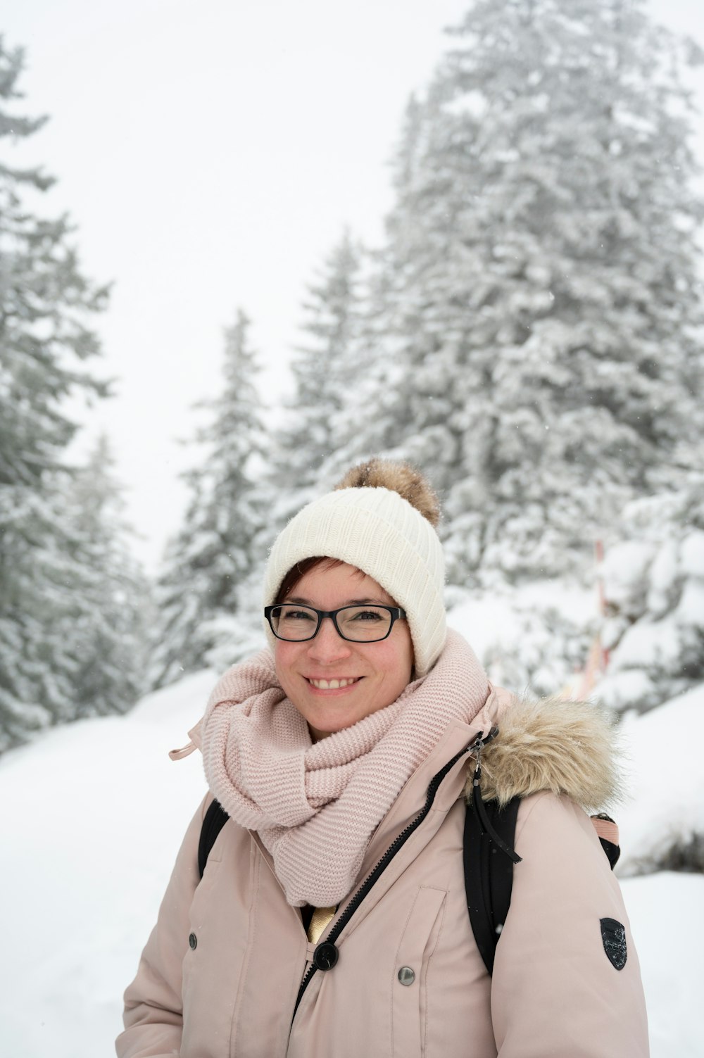 a woman wearing a hat and scarf standing in the snow