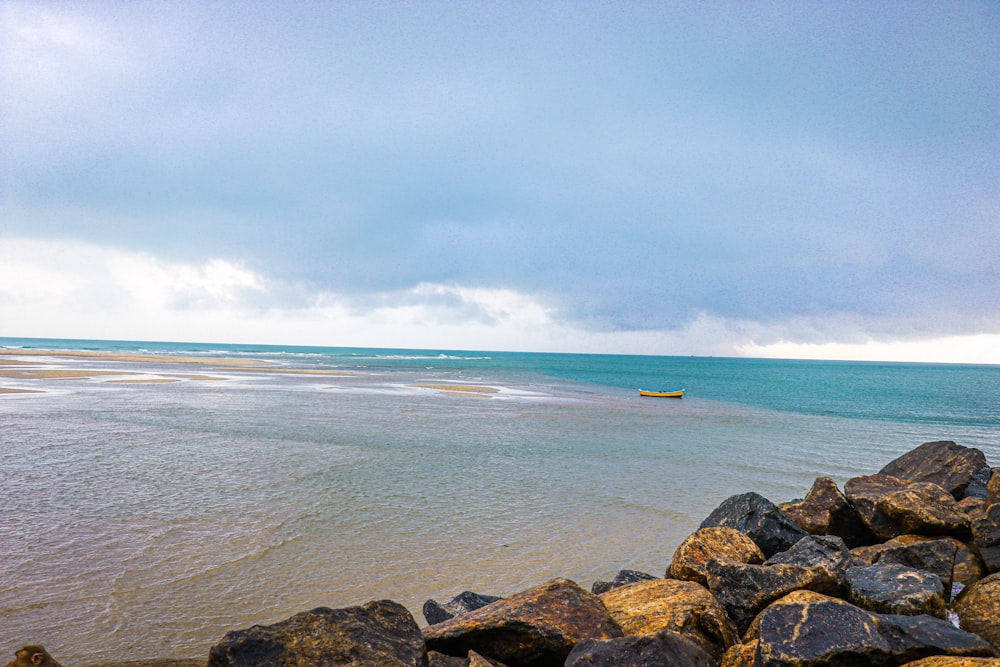 a rocky beach with a boat in the distance