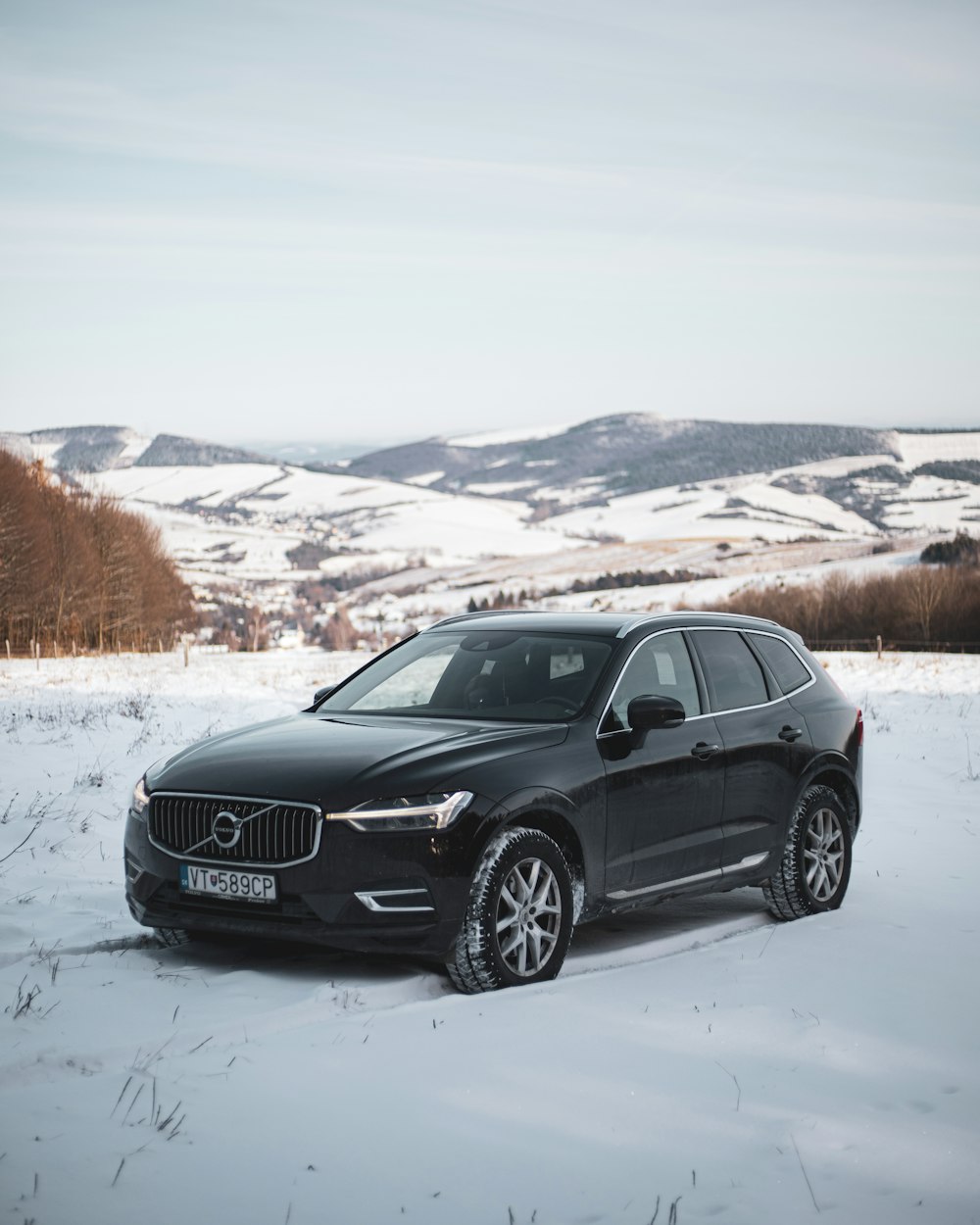 a black volvo car parked in the snow