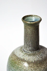 Close-up of a hand-thrown stoneware perfume bottle with bright glaze details.
