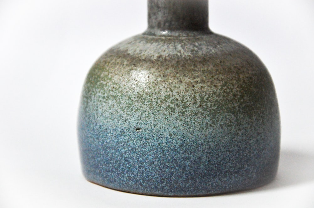 a gray and blue vase sitting on a white surface