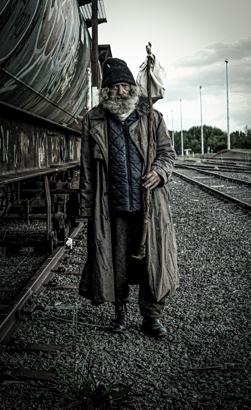 a man with a long beard standing next to a train