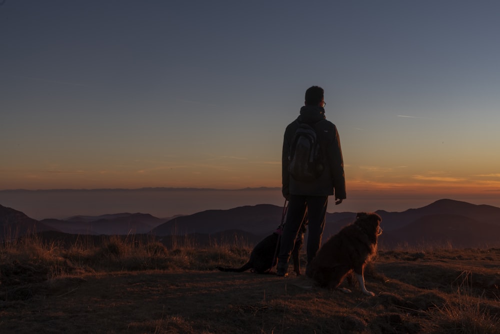 um homem de pé no topo de uma colina ao lado de um cão