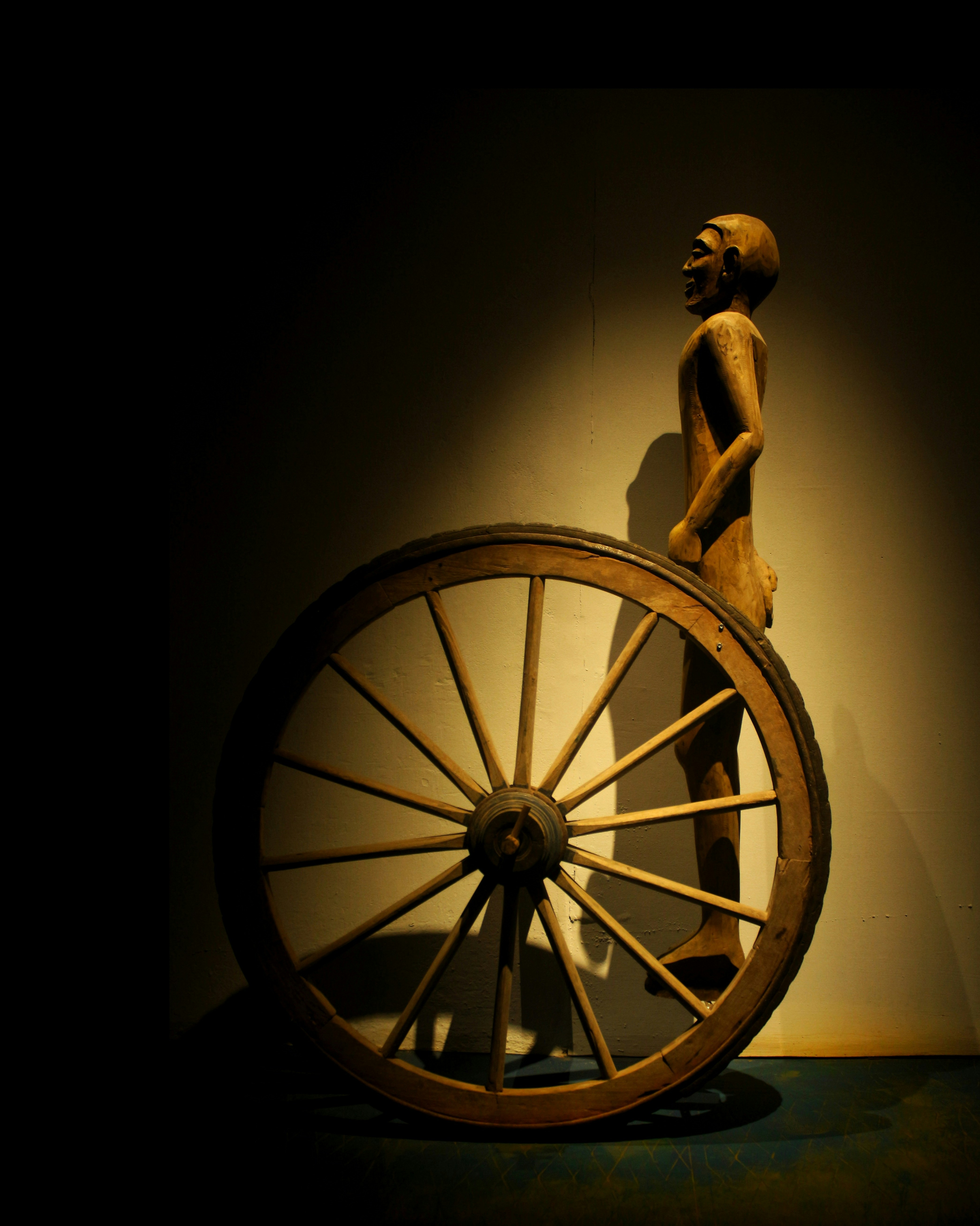 a statue of a man holding a large wooden wheel