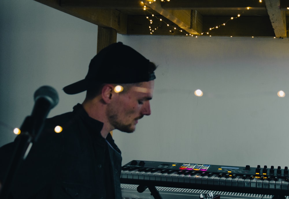 a man wearing a hat standing in front of a keyboard