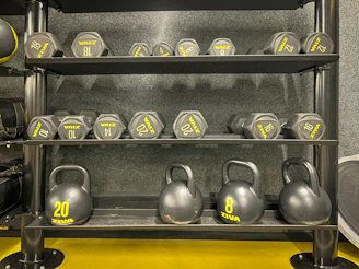 a rack of kettles and dumbbells in a gym