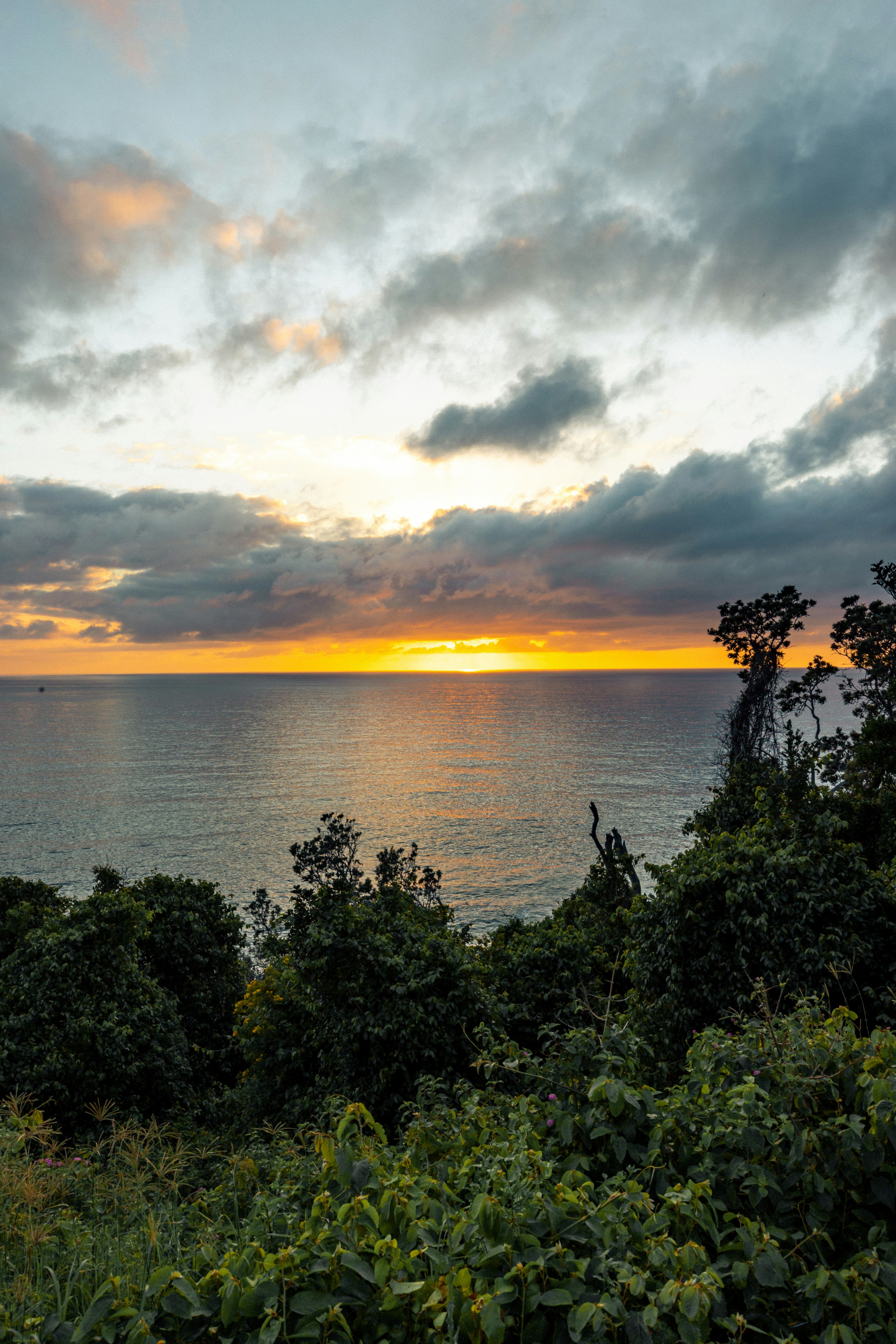 the sun is setting over the ocean on a cloudy day