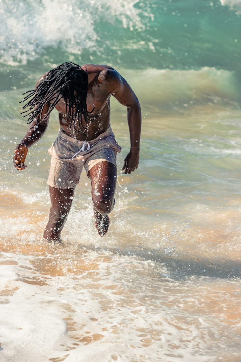 a man with dreadlocks running into the ocean