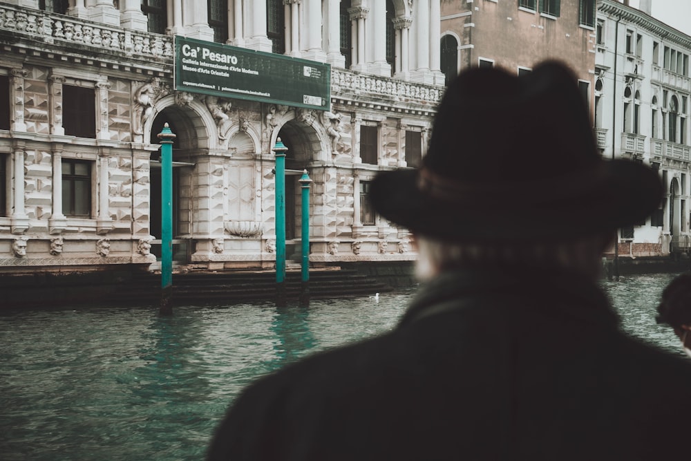 a man in a hat looking out over a canal