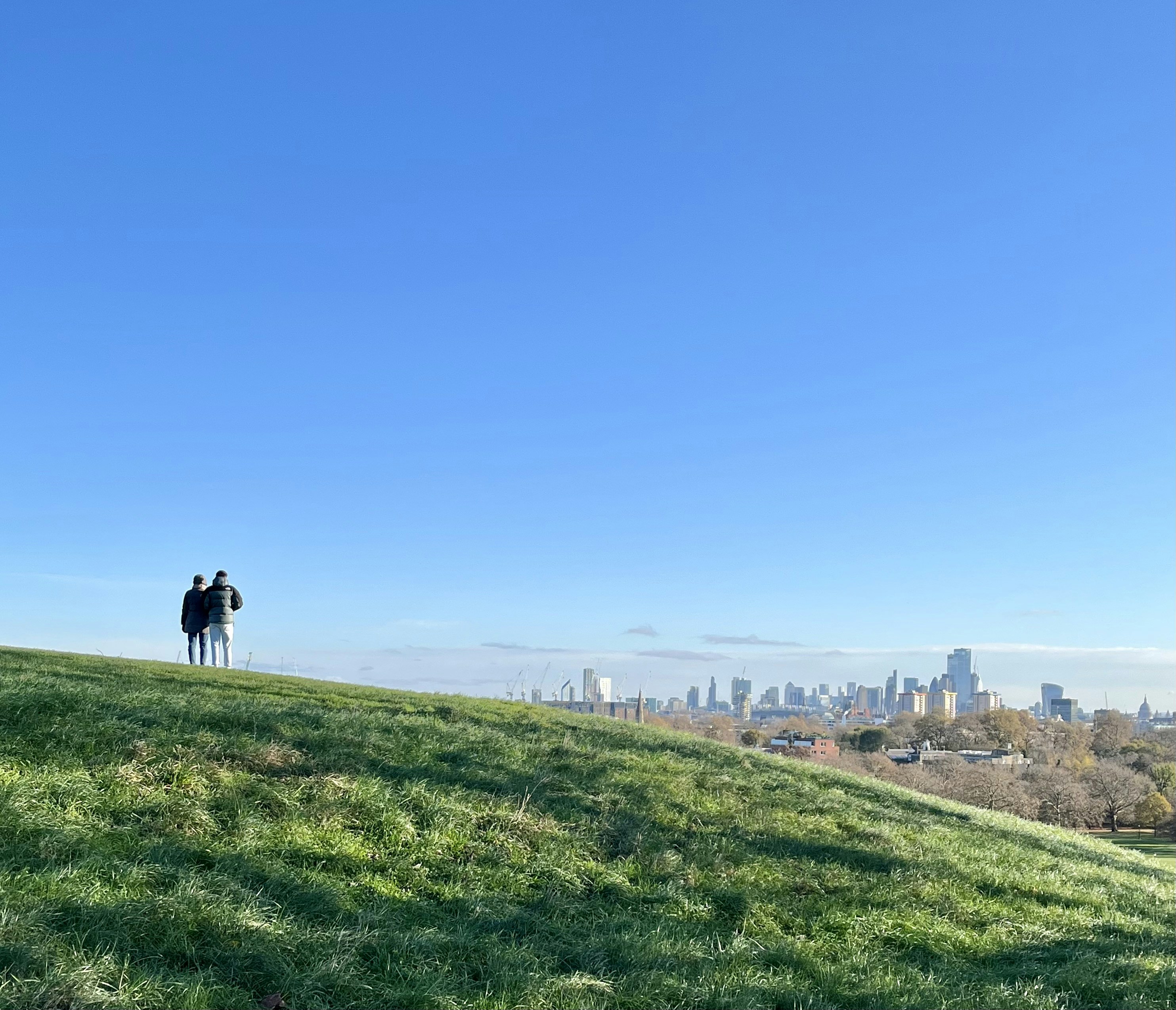 Two people standing on top of a lush green hillside photo – Free London ...