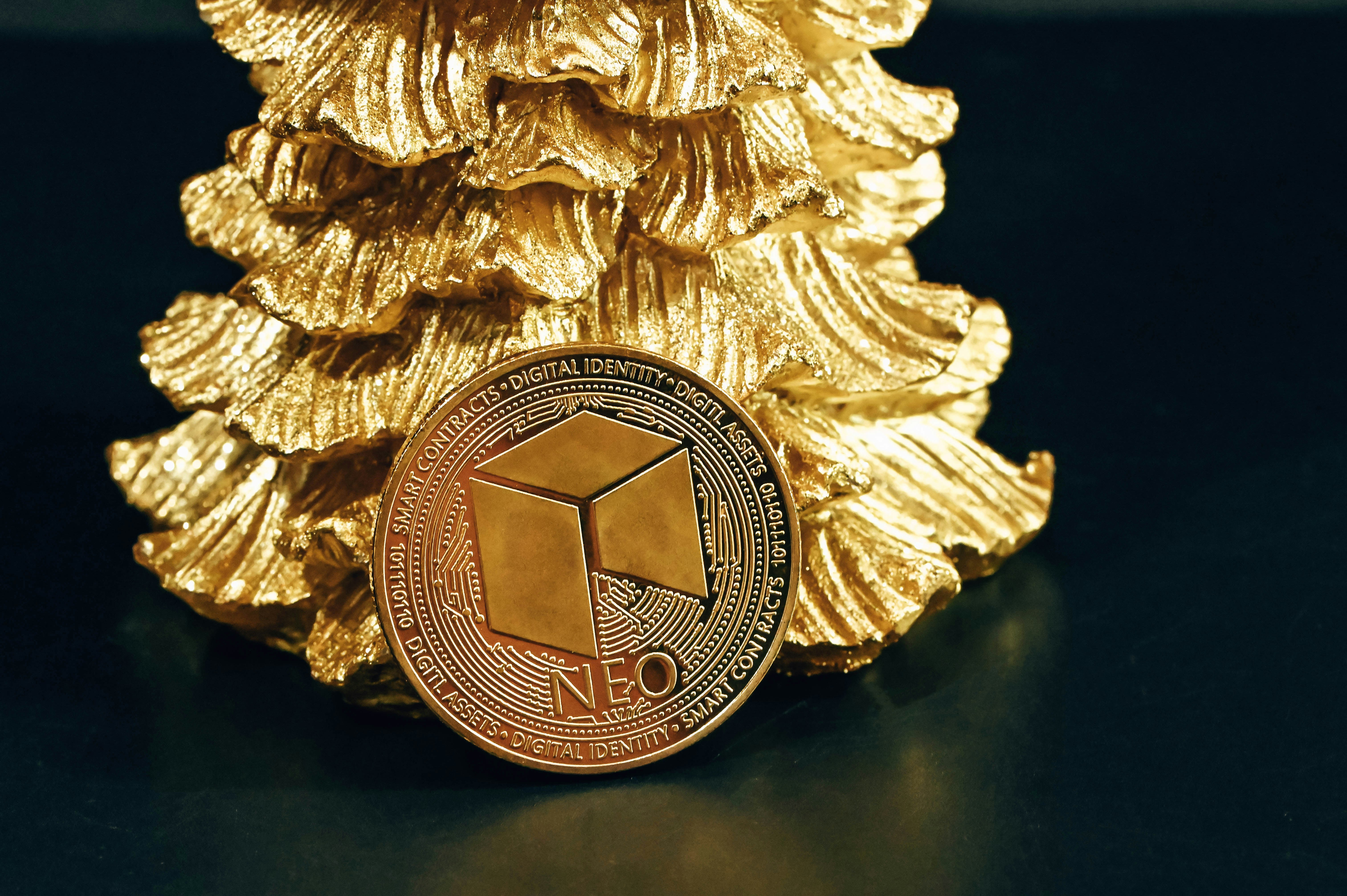 A single NEO coin leaning on a golden pine tree