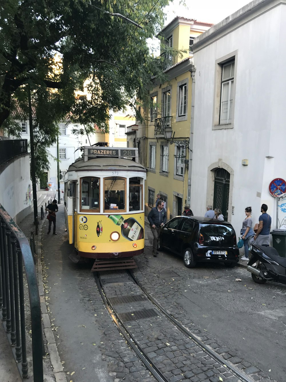 a yellow trolley car traveling down a street next to tall buildings