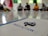 A group of people is seated on the floor in a circle, blurred in the background. In the foreground, there is a focus on a paper with the word 'INDUSACTION' written on it, and a decorative object made of rolled paper strips is placed atop it.
