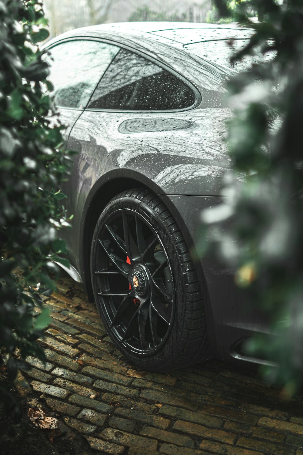 a car parked on a cobblestone road in the rain