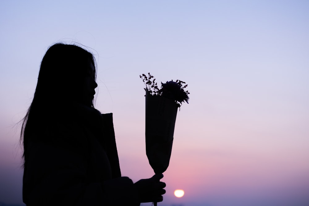 a silhouette of a woman holding a vase with flowers
