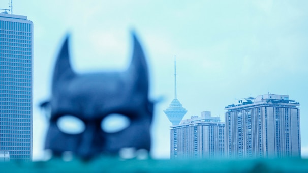 A close-up of a superhero mask with a city skyline in the background.