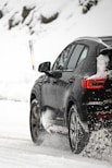 a black car driving down a snow covered road