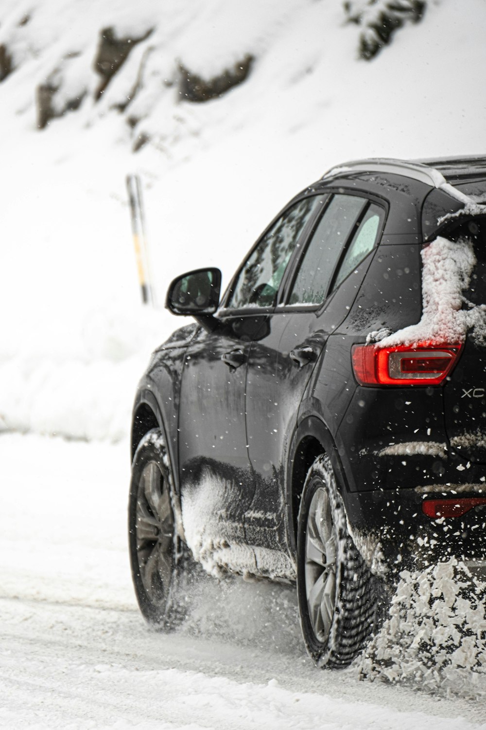 a black car driving down a snow covered road