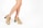 A pair of legs wearing tan high-heeled shoes against a plain white background. The shoes have laces and a chunky heel, and the model's legs are slightly crossed.