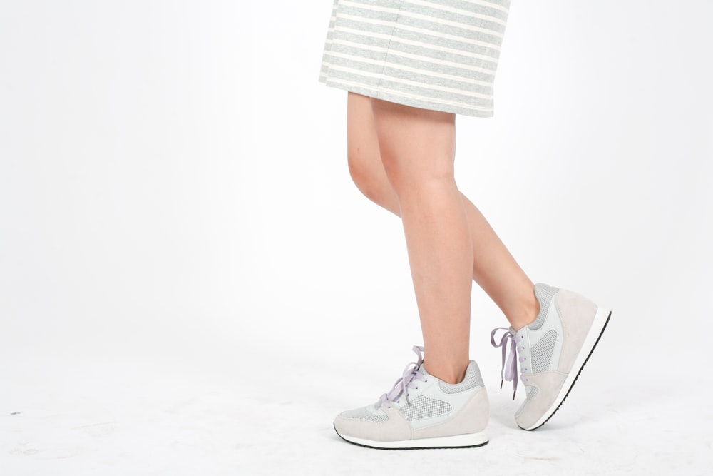 a woman in a skirt and sneakers standing on a white background