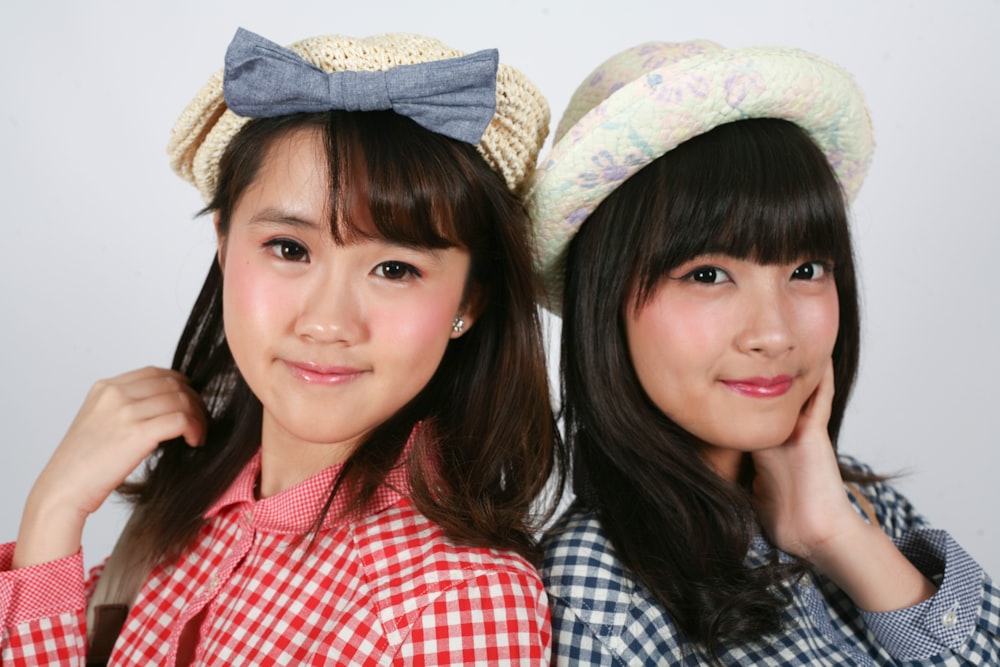 two asian girls wearing hats and posing for a picture