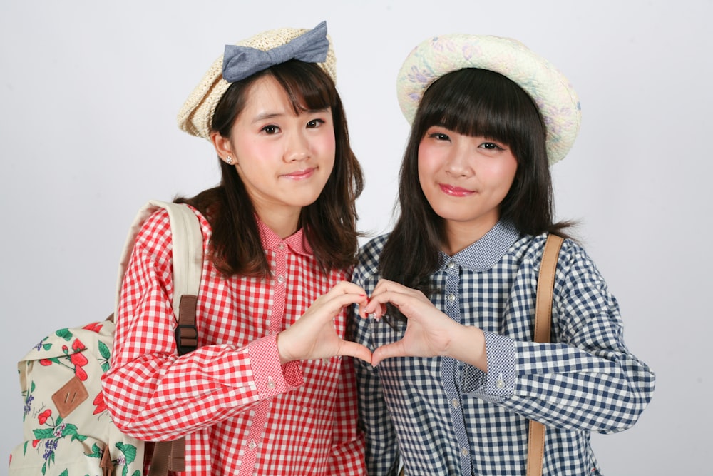 two young women making a heart with their hands